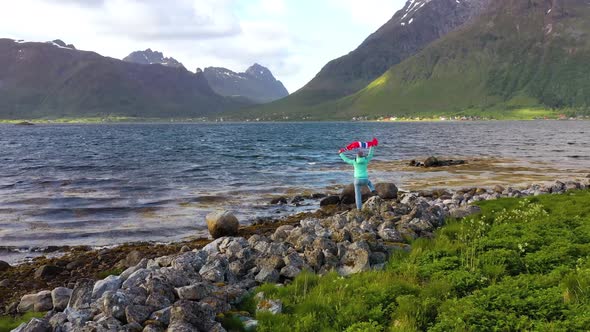 Woman with a Waving Flag of Norway on the Background of Nature alt