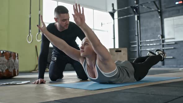 Woman Doing Back Extension Exercise with Help of Coach alt