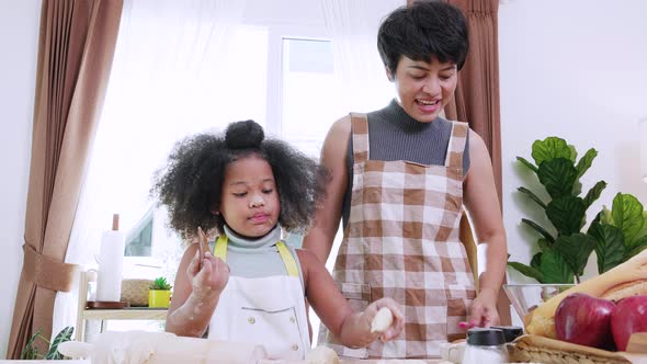 African American mom with little adorable kid preparing flour for cookie in kitchen at home.
