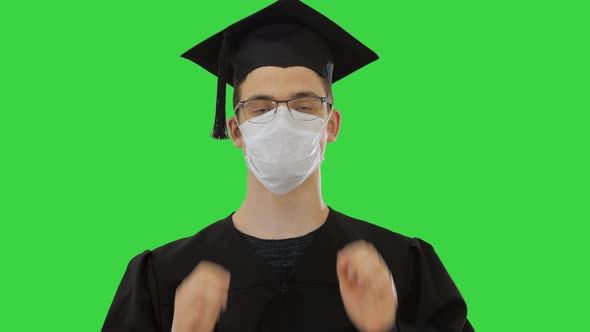 Young Man with Graduation Gown in Medical Mask on a Green Screen, Chroma Key alt