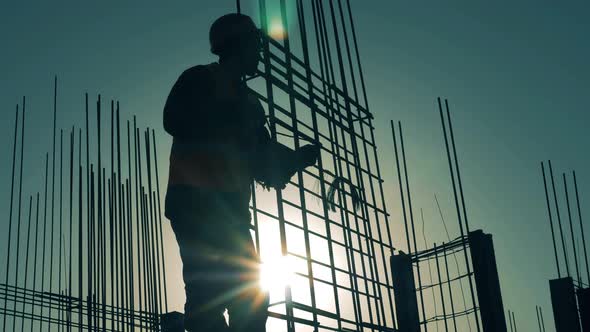 Construction Worker Works with Armature on Sunset Background. alt