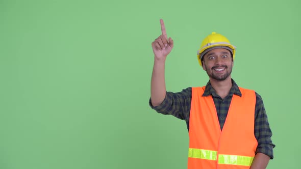 Happy Young Bearded Persian Man Construction Worker Pointing Up alt