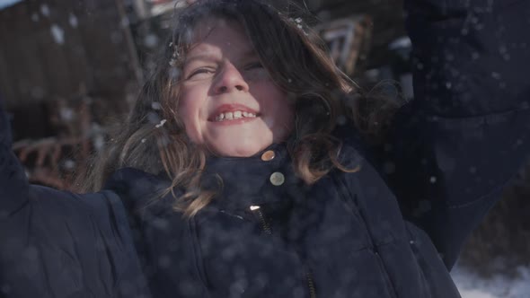Little Girl Enjoying the Winter Weather Throwing Up Snow in the Air in Slowmo alt