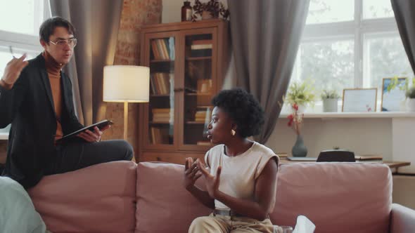 Psychologist Listening to Woman and Taking Notes on Therapy Session alt