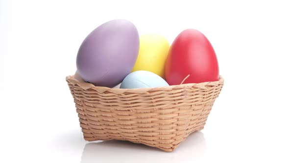 Rotating colorful easter egg in a basket isolated on white background. Close up. alt