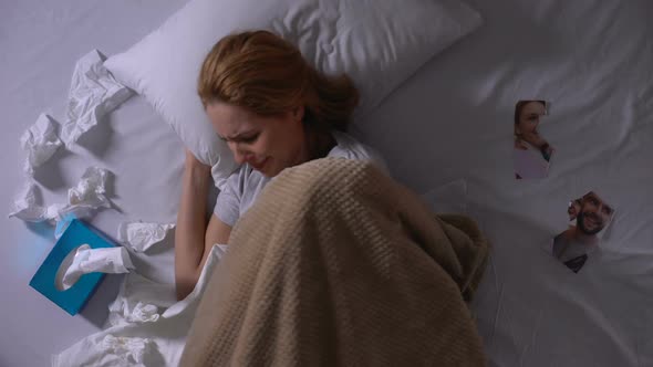 Woman Crying Lying in Bed and Looking at Tearing Photo of Ex-Boyfriend, Break-Up alt