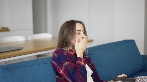 Bored Woman Checking Smart Phone Sitting on a Couch at Home alt