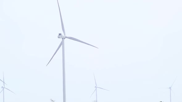 Wind generators rotate on grey sky slow-motion