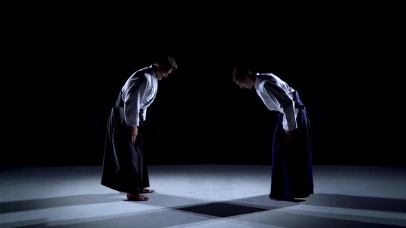 Two Masters Martial Arts Aikido Bow To Each Other. Shot Isolated on Black and White Background. alt