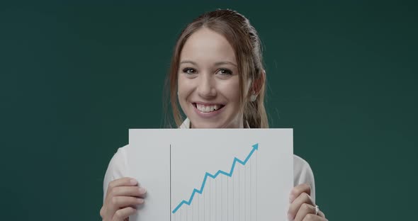 Cheerful businesswoman holding a growing financial chart with arrow going upwards