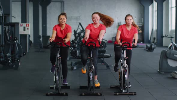 Healthy Caucasian Group of Women Exercising Workout on Stationary Cycling Machine Bike in Gym alt