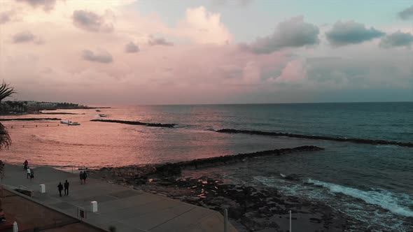 Tourists walking along promenade and enjoying vacation near calm sea at the sunset in Paphos Cyprus alt
