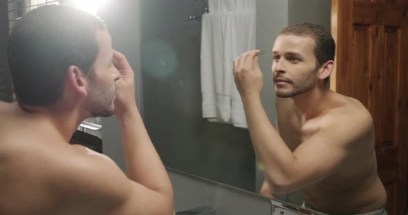Good Looking Gay Man Plucking His Eyebrows in Bathroom