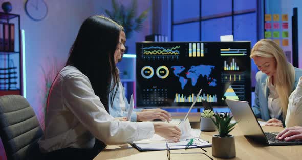 Colleagues Sitting Behind joint Workplace in Evening Office and Working on Computers alt