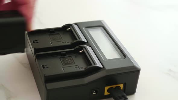 Close up Man hand installing the battery on the black charger with LED display alt