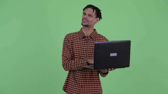 Happy Young Handsome African Man Thinking While Using Laptop alt