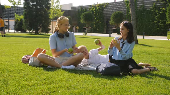 Students of Different Ages are Sitting on the Lawn in the Backyard of the School and Playing with