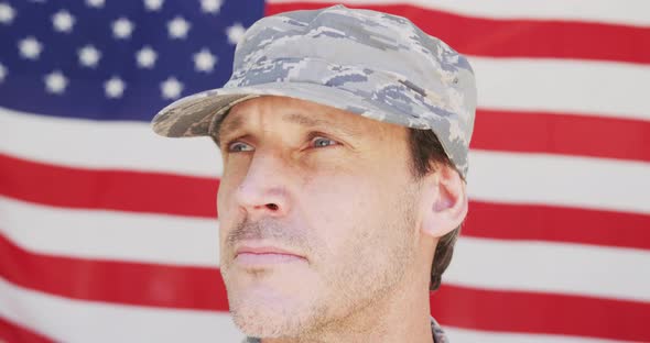 Caucasian male soldier wearing cap and looking away over american flag alt