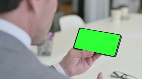 Businessman Looking at Smartphone with Green Chroma Key Screen alt