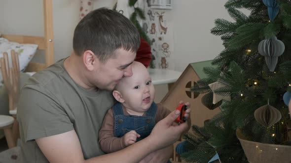 Father Showing Decorated Christmas Tree to Baby alt