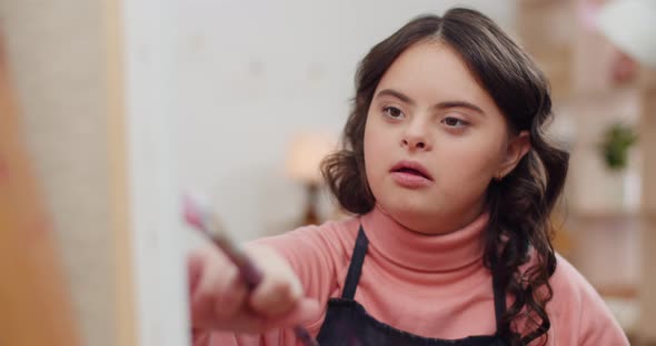 Close Up View of Talanted Girl with Down Syndrome in Painting Picture and smiling.Beautiful Teenager alt