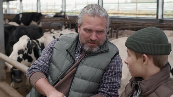 Cheerful Man Teaching Son about Running Dairy Farm alt
