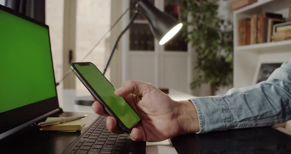 Man Using Smartphone with Green Screen at Home Office