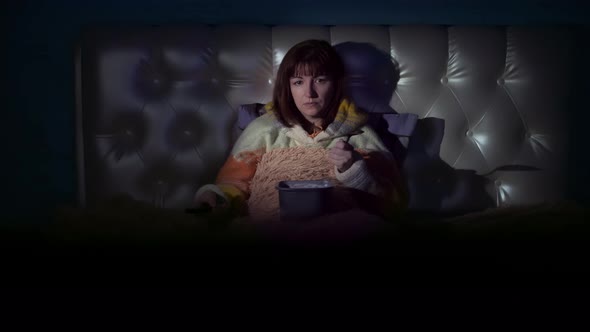Pretty Brunette Woman Watching Tv And Eating Ice Cream On The Bed In The Evening Cinematic Shot