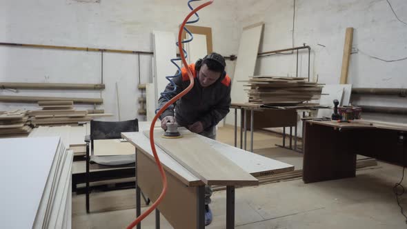 A Worker in the Furniture Industry Grinds Wood Products with a Grinder alt