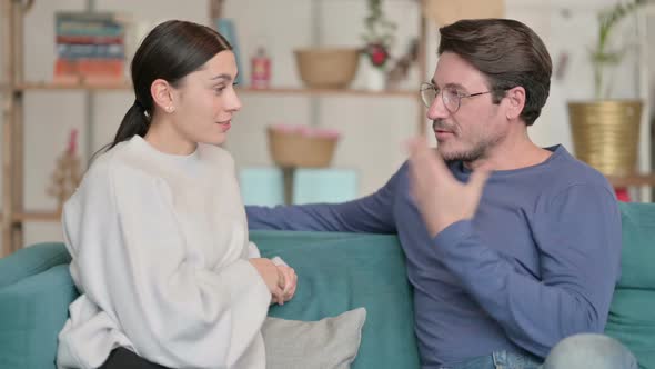 Attractive Hispanic Couple Having Conversation While Sitting on Sofa alt