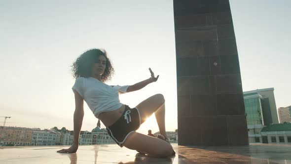 A Young Attractive Woman with Curly Hair Performing Strip Dancing Elements on the Ground Showing Her alt
