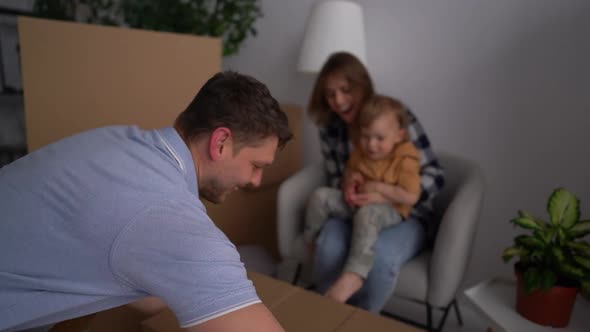First House Dad Brings in a Cardboard Box Mom and Little Son Help to Unpack alt