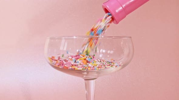 Colorful Candy Confectionery Run Poured Into a Wineglass Glass on Pink Background alt