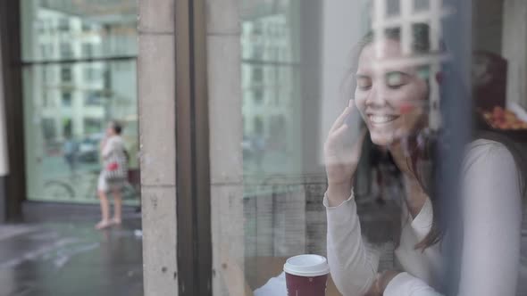 Young woman in a cafe enjoying a coffee and using a smartphone - Beautiful br alt