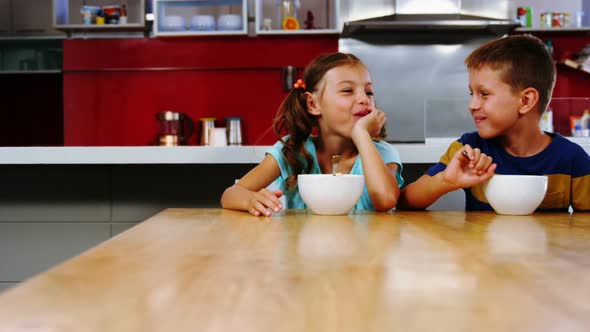 Siblings having breakfast in kitchen alt