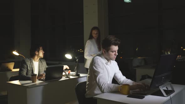 A Young Business Woman Works with Colleagues in the Office at Night