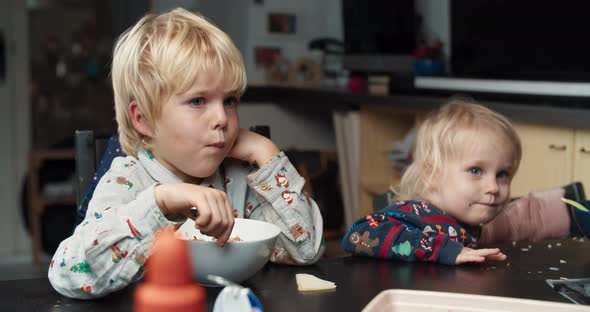 Tired Child Boy After School Eating with His Toddler Sister on Living Room