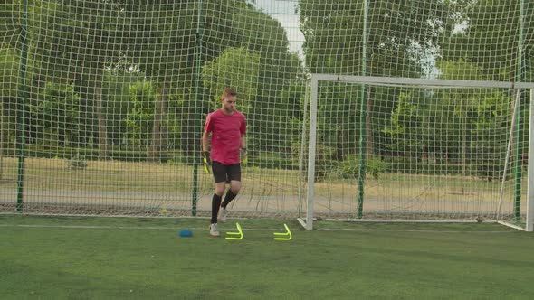 Male Soccer Goalie Performing Complex Training Catching Ball Outdoors alt
