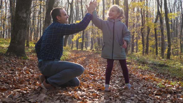 A slow motion of a father and daughter playing in an autumn forest alt