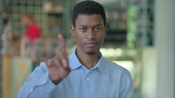 Portrait of Young African Man Saying No with Finger Sign alt
