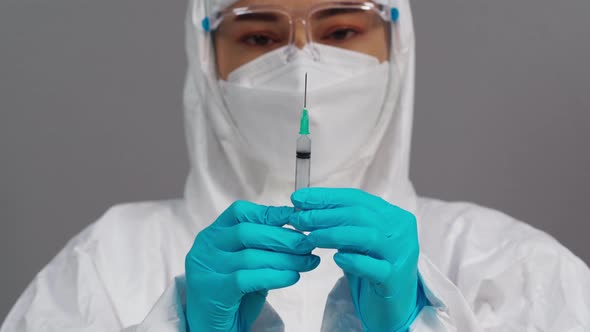 doctor in protective PPE suit holding syringe with Coronavirus(Covid-19) vaccine for injection test