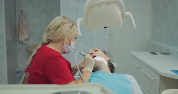 Beautiful Woman Dentist Performs Procedures for Oral Hygiene Removal of Plaque alt