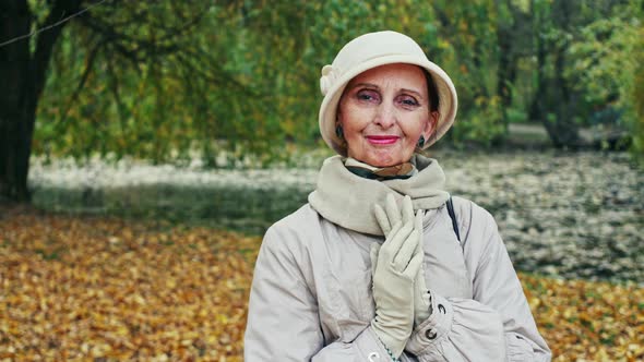 Senior Woman Posing for Camera in Autumn Park alt