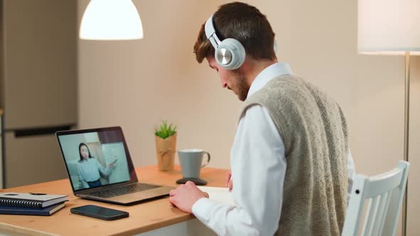 Male Student Sits at a Desk at Home and Study Online Using a Laptop Student Learns in a Remote alt