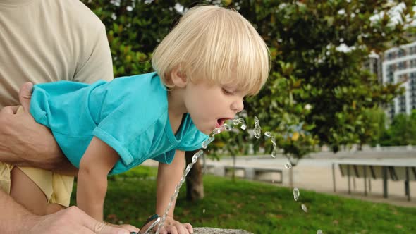 Cute Little Boy Face Portrait Drink Water in a Park From Drinking Fountain Slow Motion alt