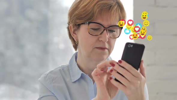 Old Woman Using Smartphone with Emojis, Smilies and Likes alt