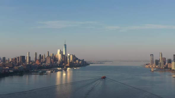 An aerial view of lower Manhattan and New Jersey from over the Hudson River at sunrise. The sun refl alt