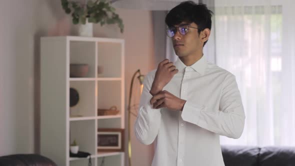 Young man gets ready for office business job, wearing white shirt, static alt