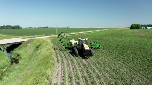Pesticide sprayer attached to farm tractor opening arms, preparing to operate. Aerial. Series alt