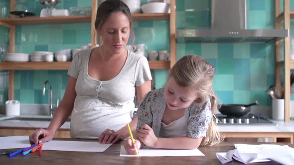 Mother and young daughter coloring together in kitchen